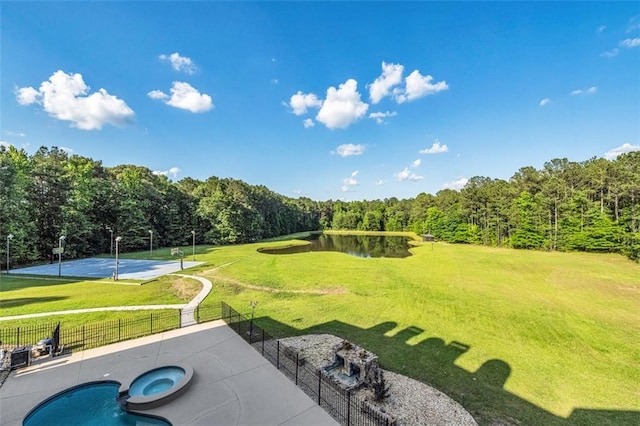 view of yard with an in ground hot tub, a water view, fence, a fenced in pool, and a patio area