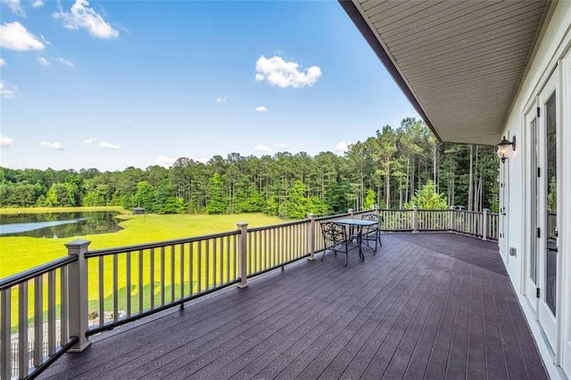 wooden deck with a water view, a lawn, and a view of trees