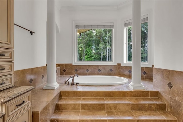 full bath with a healthy amount of sunlight, decorative columns, crown molding, and a bath