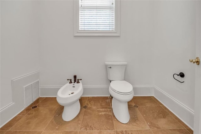 bathroom with tile patterned flooring, toilet, visible vents, baseboards, and a bidet