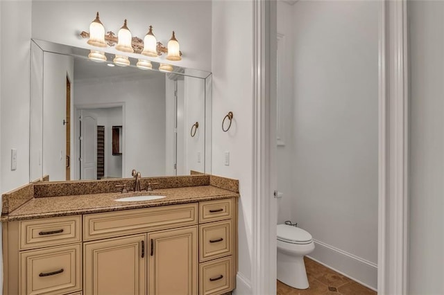 bathroom featuring baseboards, vanity, toilet, and tile patterned floors