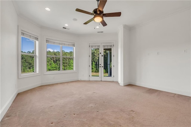 spare room with light carpet, baseboards, visible vents, and crown molding