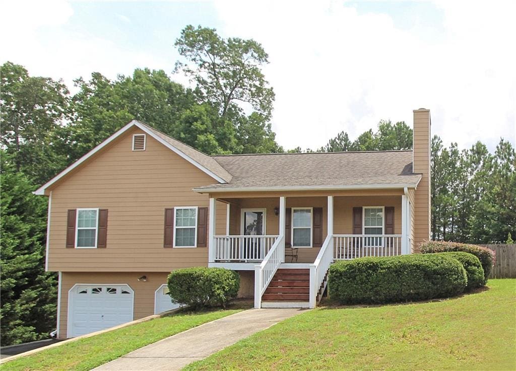 view of front of property featuring a garage, covered porch, and a front lawn