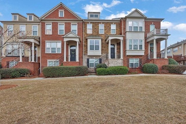 view of property featuring brick siding and a front lawn