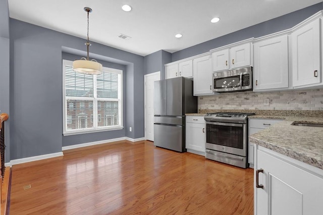 kitchen with visible vents, backsplash, white cabinets, and stainless steel appliances