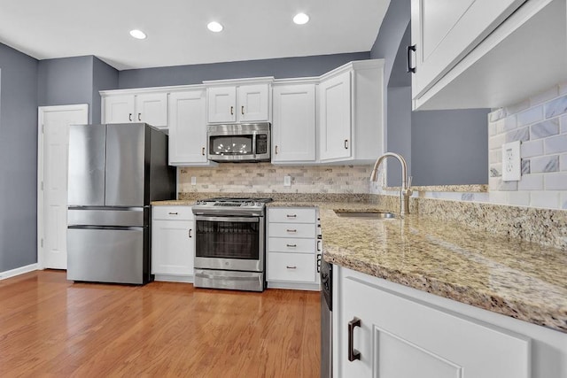 kitchen featuring tasteful backsplash, white cabinets, stainless steel appliances, and a sink