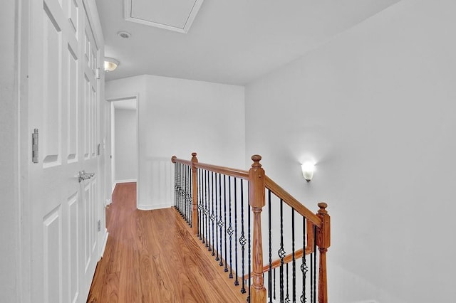 corridor with light wood-type flooring, an upstairs landing, and baseboards