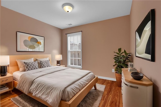 bedroom with visible vents, baseboards, and wood finished floors