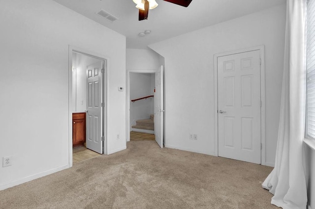 unfurnished bedroom featuring visible vents, connected bathroom, baseboards, light carpet, and a ceiling fan