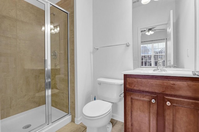 bathroom with tile patterned flooring, ceiling fan, toilet, a stall shower, and vanity