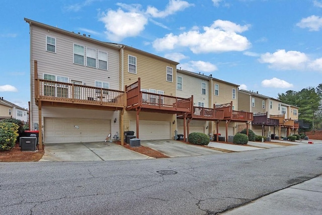 rear view of property featuring central air condition unit, an attached garage, a residential view, and driveway