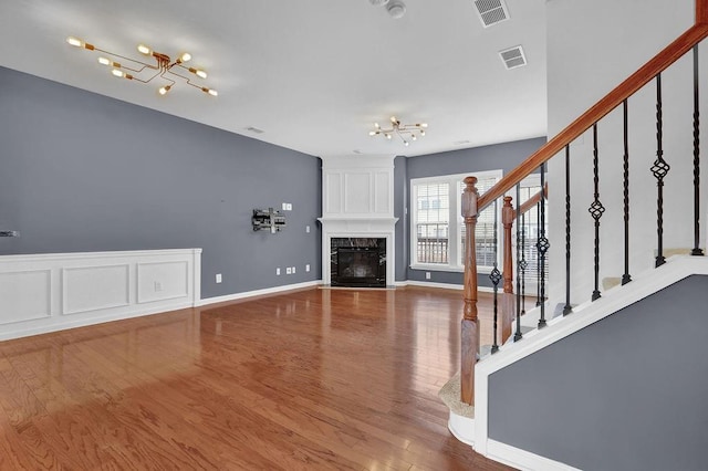 unfurnished living room featuring stairway, a notable chandelier, and visible vents