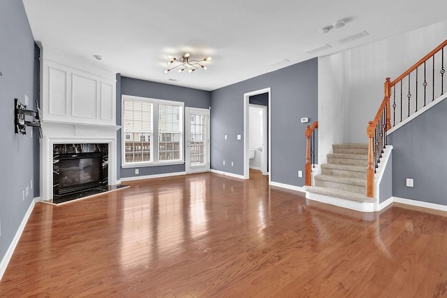 unfurnished living room with stairway, wood finished floors, baseboards, and a premium fireplace