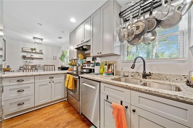 kitchen featuring white cabinetry, light hardwood / wood-style floors, stainless steel appliances, light stone countertops, and sink