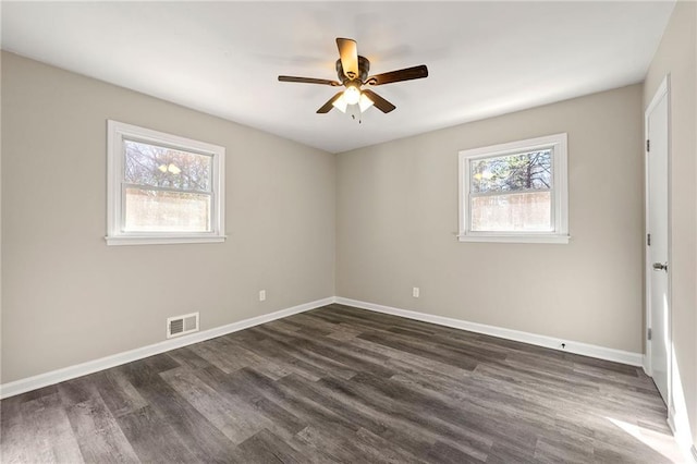 empty room with ceiling fan, dark wood-type flooring, visible vents, and baseboards