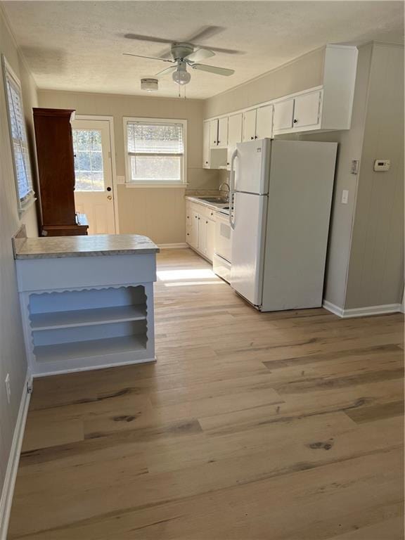 kitchen with ceiling fan, light wood-style flooring, white appliances, a sink, and white cabinets