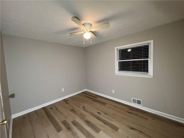 empty room with baseboards, visible vents, a ceiling fan, wood finished floors, and a textured ceiling