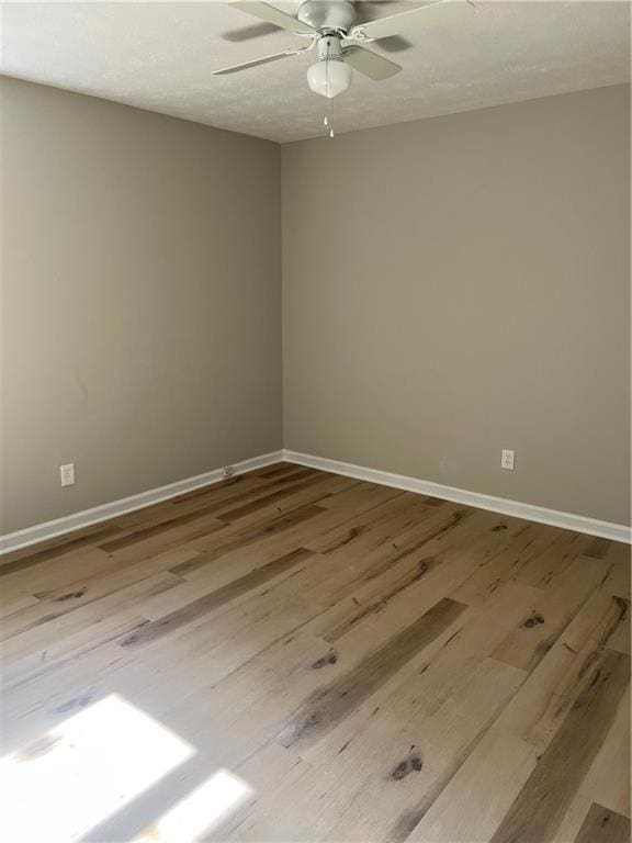 spare room featuring a ceiling fan, a textured ceiling, baseboards, and wood finished floors