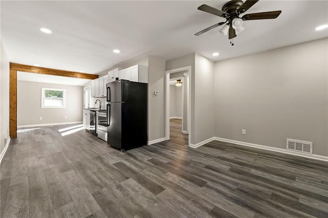 kitchen with baseboards, visible vents, white cabinets, dark wood-type flooring, and freestanding refrigerator