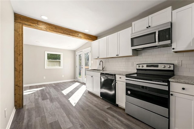 kitchen featuring stainless steel appliances, lofted ceiling with beams, decorative backsplash, a sink, and baseboards