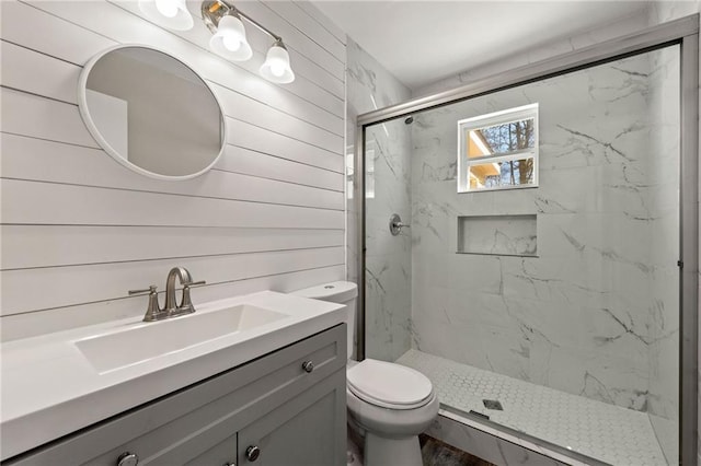 bathroom featuring toilet, a marble finish shower, and vanity