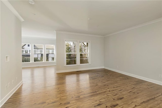 empty room with crown molding, baseboards, and wood finished floors