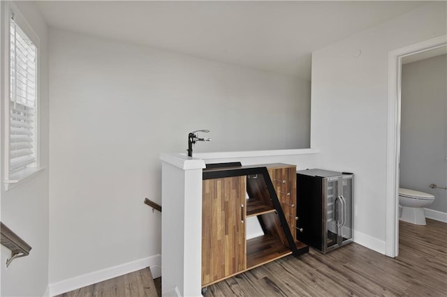 stairs featuring baseboards, wine cooler, and wood finished floors
