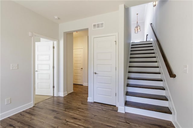 staircase with baseboards, visible vents, and wood finished floors