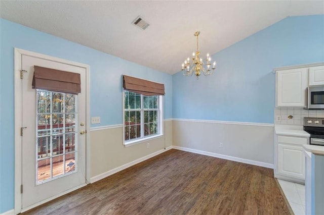 kitchen with light wood-type flooring, vaulted ceiling, stainless steel appliances, and white cabinetry