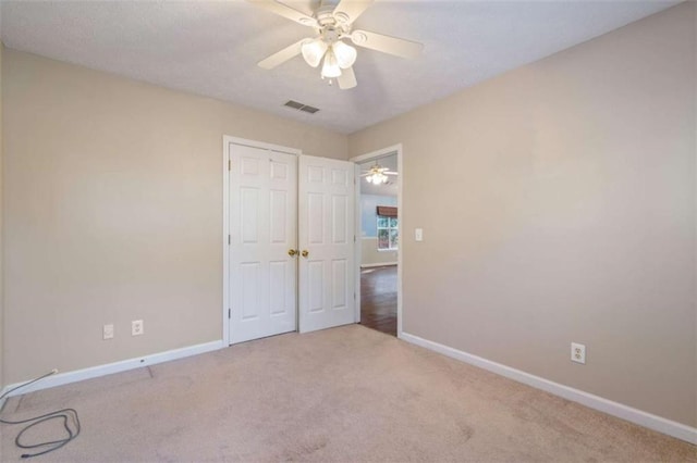 unfurnished bedroom featuring ceiling fan, light colored carpet, and a closet