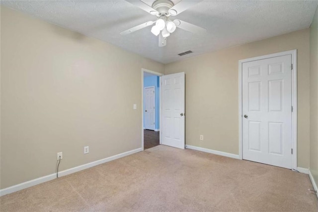 unfurnished bedroom featuring a textured ceiling, ceiling fan, and light carpet