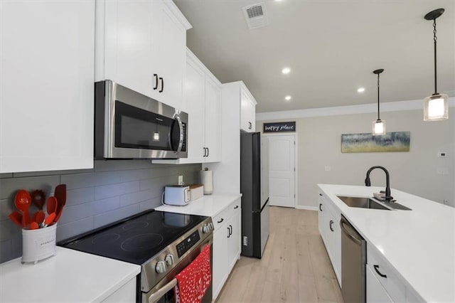 kitchen featuring white cabinetry, appliances with stainless steel finishes, sink, and pendant lighting