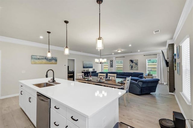 kitchen featuring sink, crown molding, hanging light fixtures, stainless steel dishwasher, and a kitchen island with sink