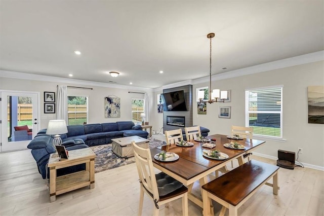 dining room featuring plenty of natural light, ornamental molding, a fireplace, and light wood-type flooring