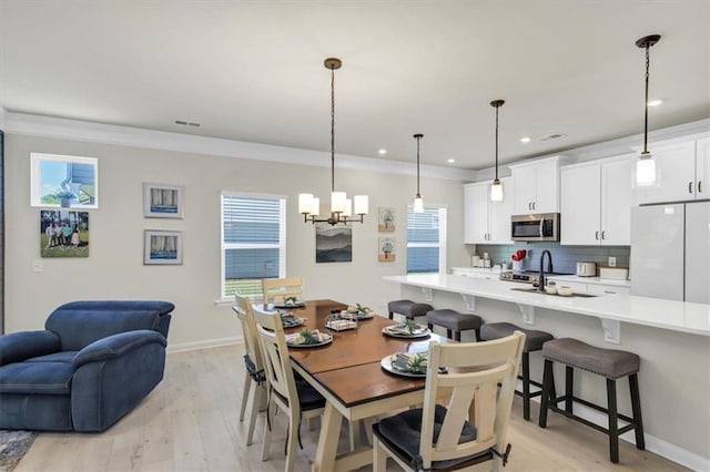 dining space with crown molding, a chandelier, and light hardwood / wood-style floors