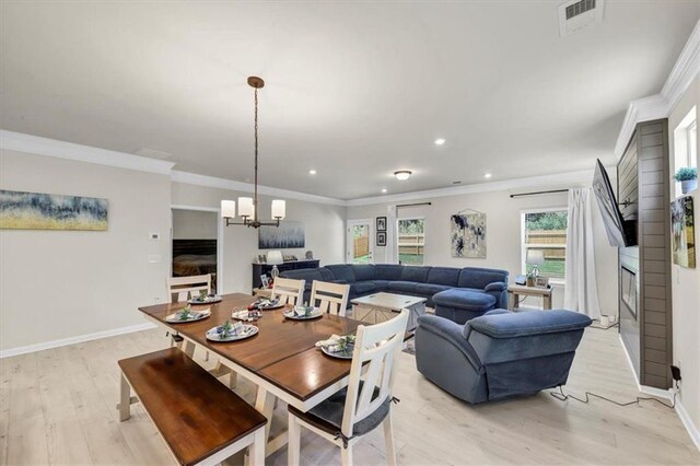 dining area with crown molding, a notable chandelier, and light wood-type flooring