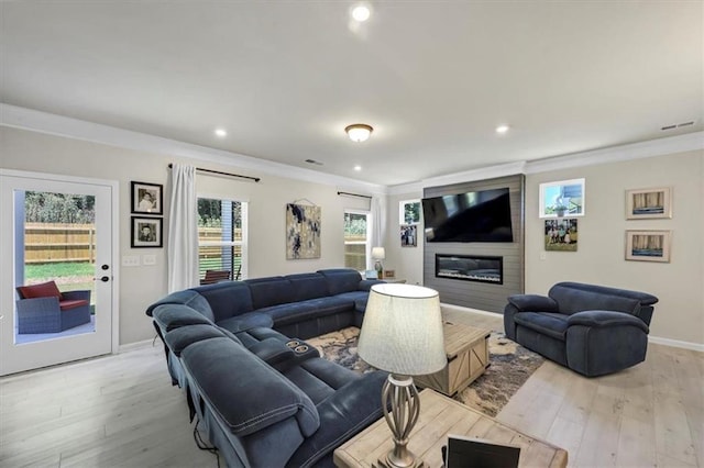 living room featuring ornamental molding, a large fireplace, and light wood-type flooring