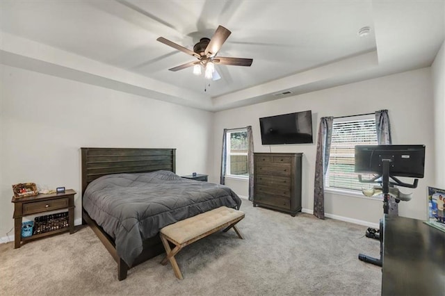 carpeted bedroom featuring a raised ceiling and ceiling fan