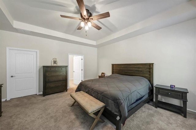 carpeted bedroom featuring a raised ceiling and ceiling fan