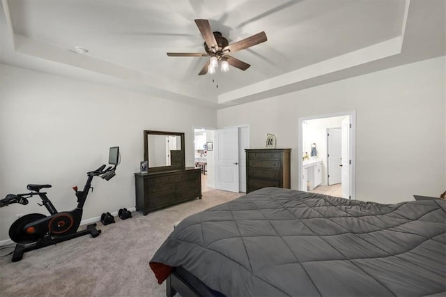 carpeted bedroom featuring ceiling fan, ensuite bathroom, and a raised ceiling