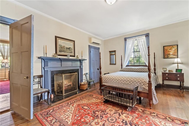 bedroom featuring ornamental molding, a wall mounted air conditioner, hardwood / wood-style flooring, and a tile fireplace