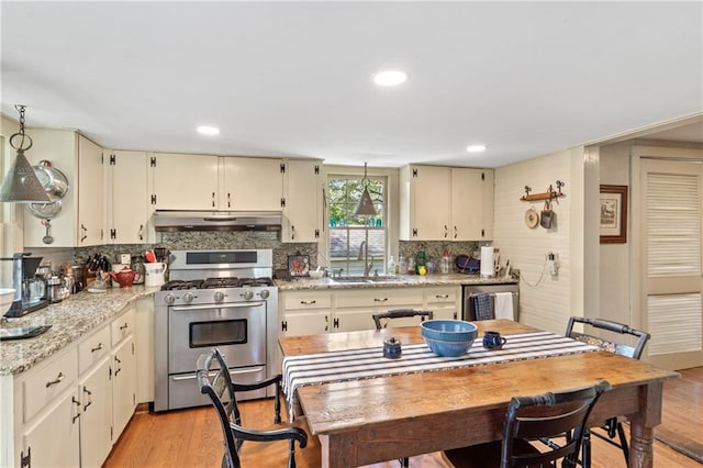 kitchen with light stone counters, cream cabinets, stainless steel appliances, and light hardwood / wood-style floors