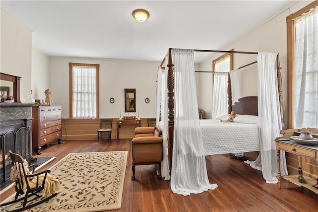 bedroom with wood-type flooring, ornamental molding, and multiple windows