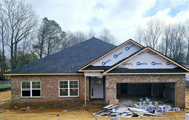 view of front of home featuring a garage, brick siding, and roof with shingles