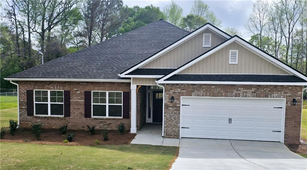 view of front facade featuring brick siding, a front yard, a garage, and driveway