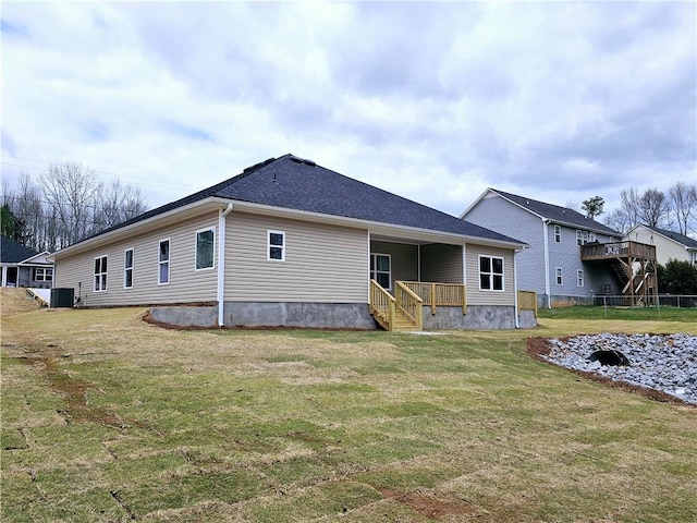 rear view of house with a yard, fence, cooling unit, and a shingled roof