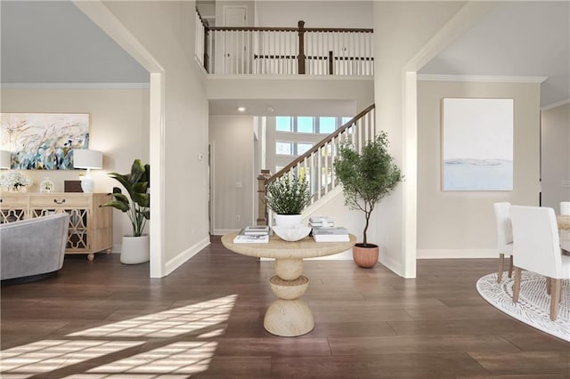 foyer featuring dark wood-type flooring, ornamental molding, and a high ceiling