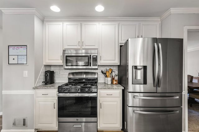 kitchen with white cabinets, visible vents, stainless steel appliances, and decorative backsplash