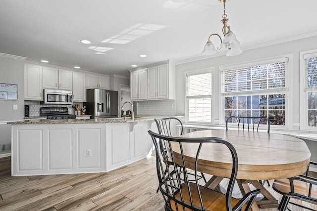 kitchen featuring crown molding, visible vents, backsplash, appliances with stainless steel finishes, and light wood-style floors