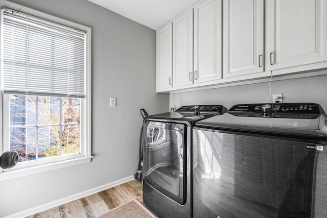 clothes washing area featuring cabinet space, baseboards, light wood-style floors, and washer and dryer